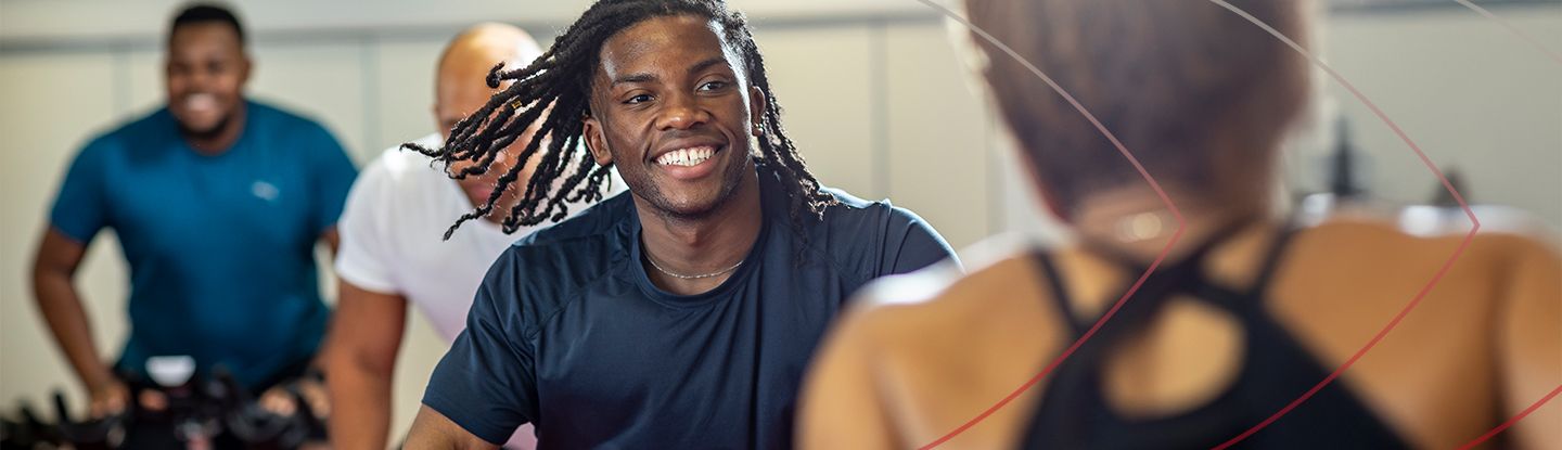 People smiling and enjoying a group cycling class at CitySport gym.
